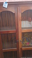 Close-up of teak cabinet double doors with vertical slats, showing hardware and wood detail.
