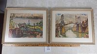 Two framed lithographs side by side with visible mats and frames on a patterned wall. Both artworks show colorful detailed prints of landscapes and architecture.