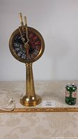 Full view of brass nautical ship’s telegraph on table next to soda can for size comparison, showing height and shape