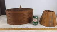 Full view of both wooden basket weave lamp shades on table with soda can for scale.