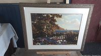 Framed art print featuring a colorful garden terrace with roses overlooking the sea, in an ornate gallery frame.