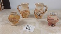 Four Namadji Earth pottery items: two small vases and two jugs on a beige fabric surface.