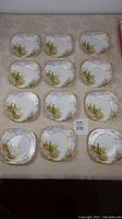 12 Royal Albert Kentish Rockery bread and butter plates arranged in a 3 by 4 grid on a beige cloth.