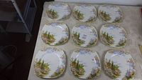 Nine square plates arranged in a 3x3 layout showing scenic floral countryside pattern