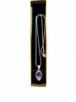 Full view of the amethyst pendant necklace placed in gold-colored presentation box with ribbon inside.