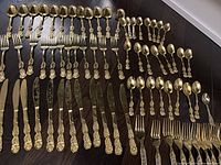 Full layout of all 73 pieces cutlery arranged by type on dark surface.