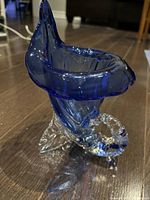 Side angle shot showing blue upper section and clear spiral base of the conch shell glass sculpture.