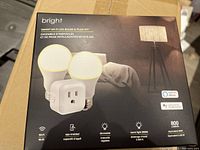 Box front showing two smart LED bulbs and one smart plug, with key features like Wi-Fi, app control, dimmable, warm light 3000K, 800 lumens, compatible with Alexa and Google Home.