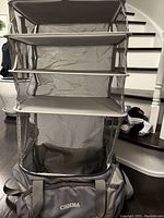 Photo of the gray collapsible hanging organizer with multiple mesh shelves and the fabric labeled CHHMA