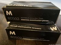 Photo of two boxes of Finitex black nitrile powder-free medical exam gloves, size Medium, showing the side labeling.