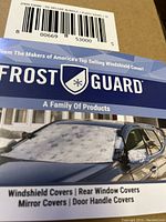 Box showing Frost Guard branding, demonstrating windshield and mirror covers with puppy paws design on a car.