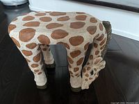 Full view of the giraffe plant stand/stool from above and front showing the pattern and shape.