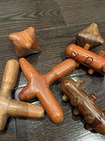 Close-up view of six wooden hand massage tools with varying shapes and finishes arranged on wooden floor.