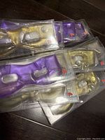 Twelve new reusable gel eye masks in gold and purple colors, individually packaged, showing the heat activation button.