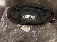 Front view of black Dem Official waist pack showing logo patch and zipper pocket.