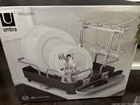 Boxed Umbra Holster dish rack showing assembled dish rack with space for plates, utensils, and glassware.