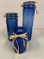 Overall view of three blue glass jars illustrating different sizes and styles including clamp lids and one with a ribbon.