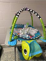 Full view of colorful baby play mat on table with play arches and bottle on top
