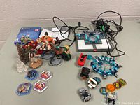 Overall view of Disney Infinity figurines, gaming portal, cables, Lego figurines and accessories on table