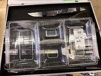 Barbecue set case with visible utensils: stainless steel knife with black handle and cleaning brush. Clear plastic tray with five compartments and signs of wear and scratches.