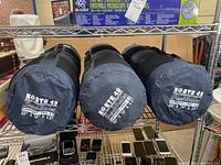 Three rolled and bagged North 49 brand sleeping pads in dark cylindrical bags, showing size and branding on bags.
