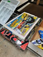 Two boxed toy car racing sets stacked showing Tyco California Classics on top and Formula-1 Championship underneath with visible toy cars beside them.