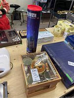 Photo showing the coffee canister labeled Fallsview Resort beside the box of porcelain mugs and the tube holding Riedel tumblers.