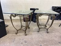 Side view showing one of the end tables with glass top and ornate metal base with scrollwork design.