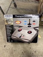 Front view of the box displaying the Homedics TherapistSelect Deluxe Programmable Percussion Foot Massager with Heat, showing main features on packaging.