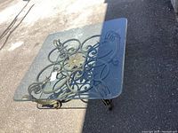 Top view of ornate metal base with central floral design and curved legs on glass top surface.