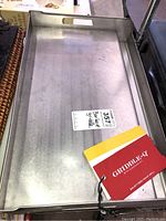 Top-down view of the rectangular metal barbecue griddle showing the full cooking surface and raised edges with cut-out handle.