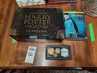 Photo of The Complete Harry Potter Collection book box, DVD set, and collectible tokens on table