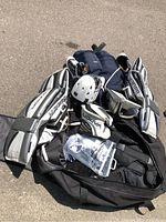 Photo showing full set of men's goalie equipment including pads, helmet, chest protector, pants, skates, and black Koho bag