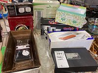 Wide view showing the full assortment of kitchen and dining items stacked together including tin baskets, Fitz and Floyd box, recipe box, vacuum flask, and glassware.