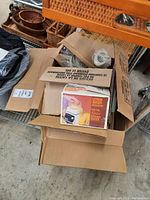 Open cardboard box containing boxed Oster Citrus Juicer Accessory with original packaging visible, along with other appliance parts and packaging material.