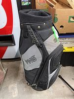 View of Ping golf bag showing black and gray color with Ping name embroidered, side handle and textured details.