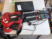 Two RedOctane Guitar Hero wireless guitar controllers with attached cables and straps laid on table