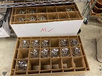 Two cardboard storage boxes with 24 total clear glass wine glasses, each in its own compartment, view from above.