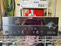 Front view of Yamaha AV receiver showing model name, display, buttons, and volume knob.