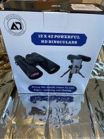 Box front showing brand Adasion and model 12x42 powerful HD binoculars with phone holder graphic.