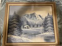 Full view of the Philip Klaus oil painting showing the framed winter mountain scene with cabin and pine trees.