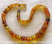 Full view of natural amber rondelle necklace showing coloration and graduated bead sizes, coiled on fabric background.