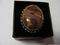 Front view of the ring showing large brown oval stone with bezel and bead detailing on sterling silver band.