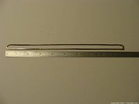 Full view of silver chain extended beside a ruler measuring 20 inches.