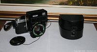 Pentax ME Super camera body with Ricoh AF flash lens and black carrying case on displayed surface.
