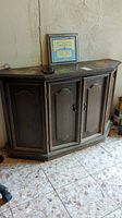 Front view of wooden cabinet with two paneled doors and metal handles, showing overall condition.