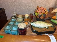 Table display with assorted candles, blue glass tealight candle holders, Asian figurines and statues, and the Big Mouth Billy Bass singing fish plaque