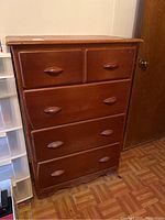 Front view of wooden chest of drawers showing all four drawers and curved wooden handles.