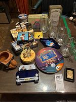 Photo shows all items from lot including Camel tins, cigarette boxes, glass beer steins, ceramic camel, novelty ashtray, metal advertising plate, lighter.