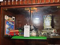 Full view of die cast vehicles including red double decker bus and cars behind glass cabinet